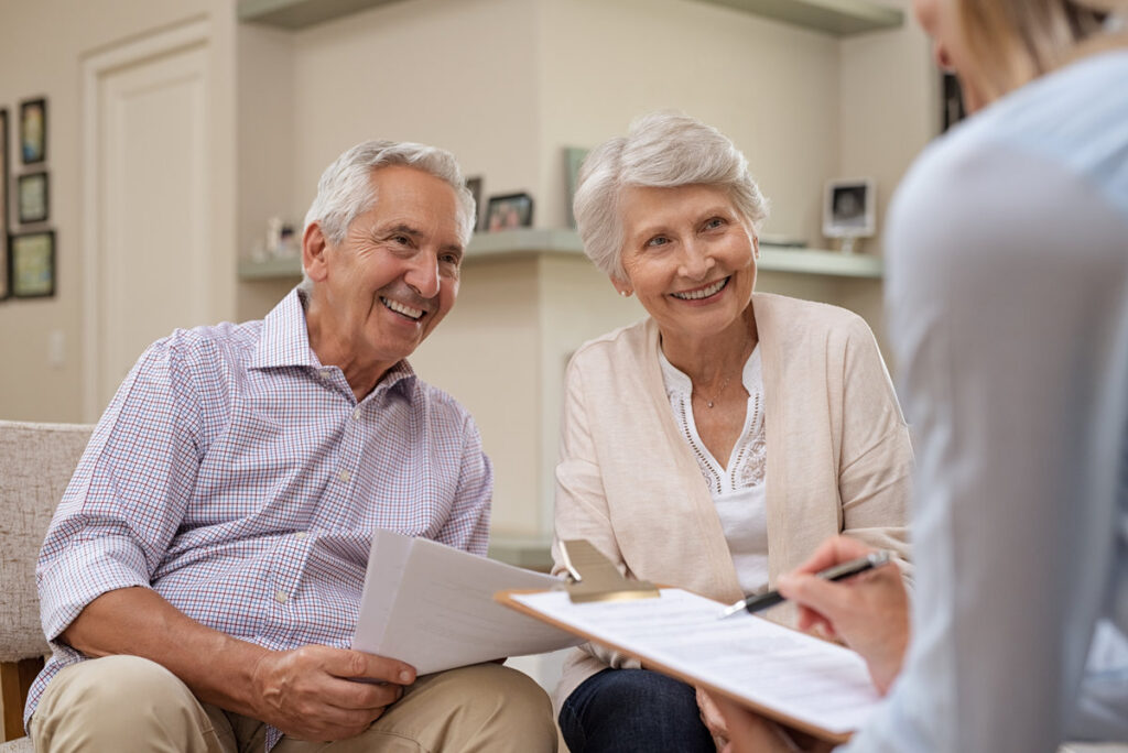 Senior couple meeting real estate agent at home. Old husband and wife with financial advisor for investment opportunities. Happy elderly man and woman listening to various investment plans for their retirement.
